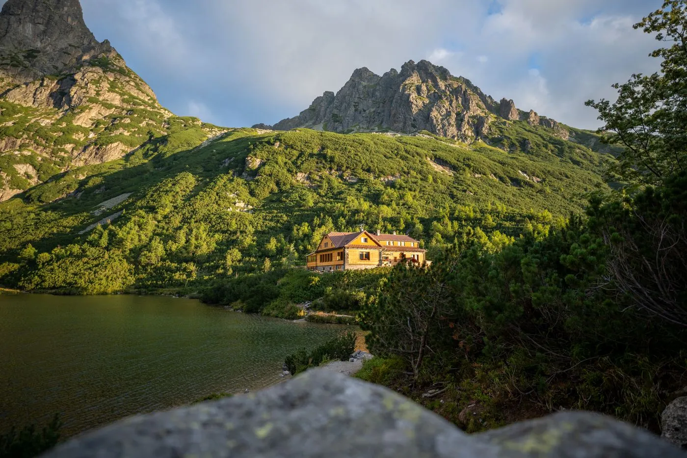Horská chata u jezera pod skalnatým štítem