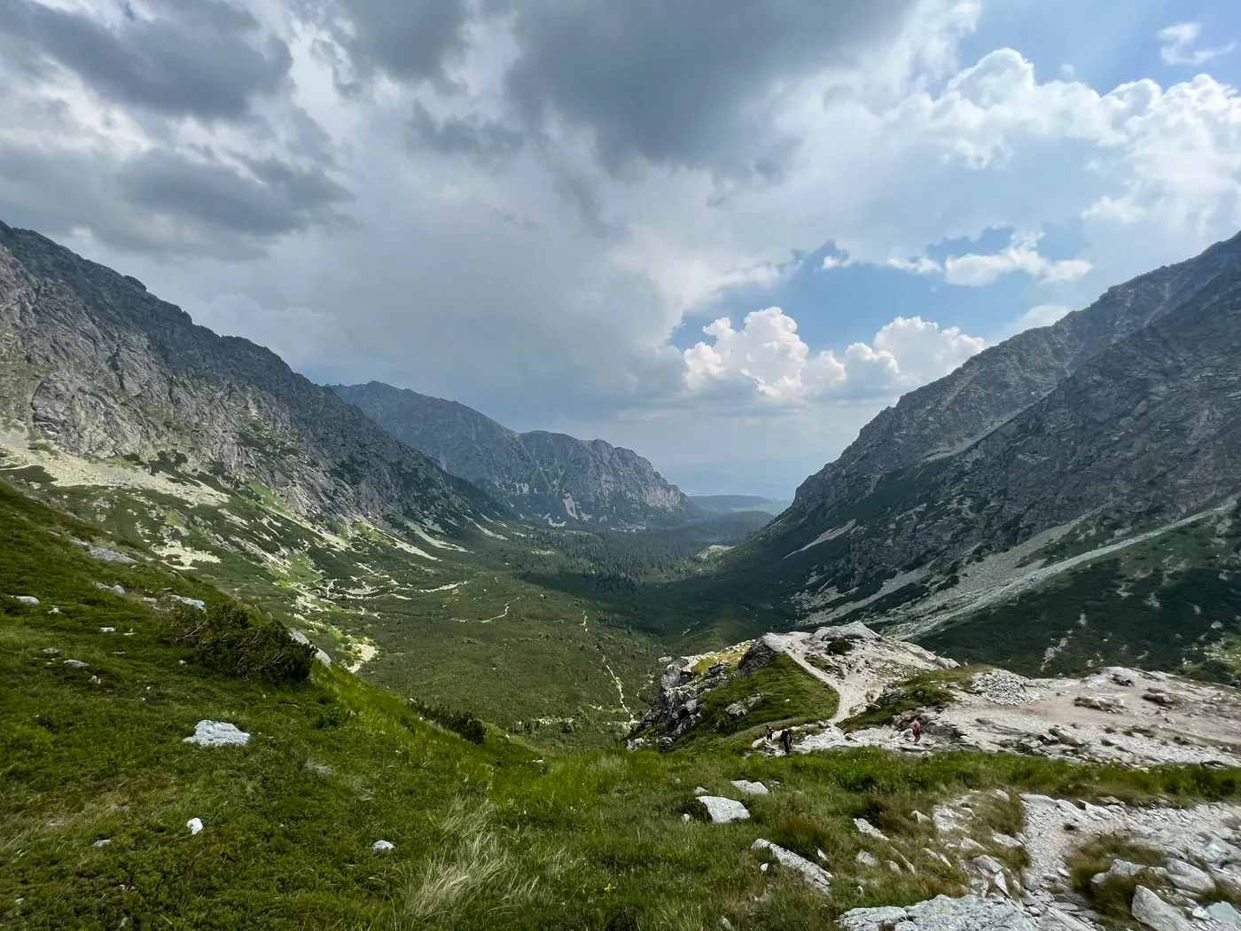 Horské údolí se zelenými svahy a turistickou cestou