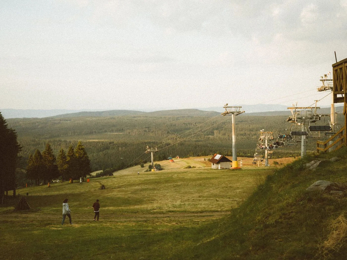 Sedačková lanovka nad zvlněnou krajinou luk a lesů