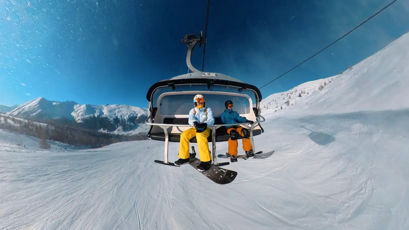 Snowboardisté na sedačkové lanovce nad svahy