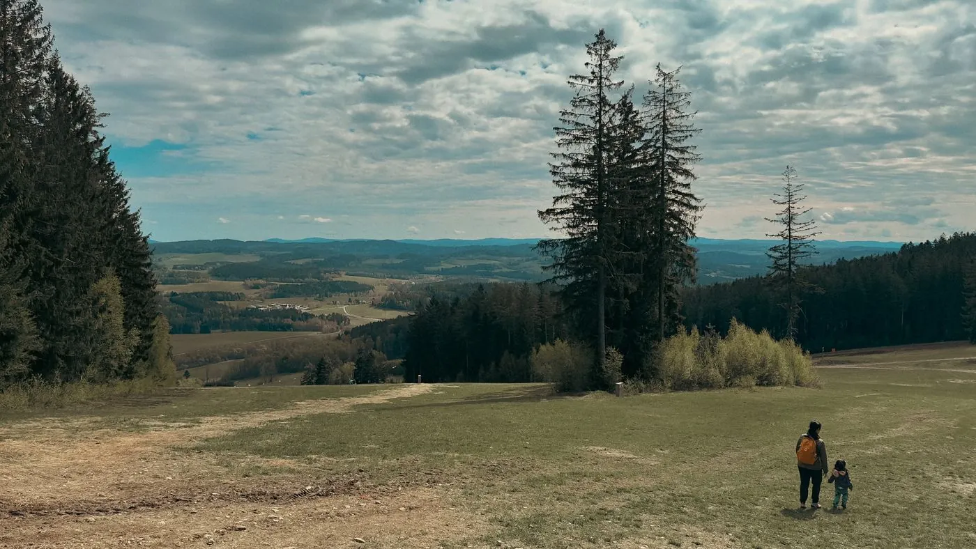 Matka s dítětem na louce nad zvlněnou krajinou