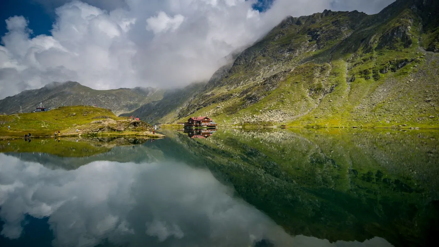 Horské jezero s odrazem oblak a chat