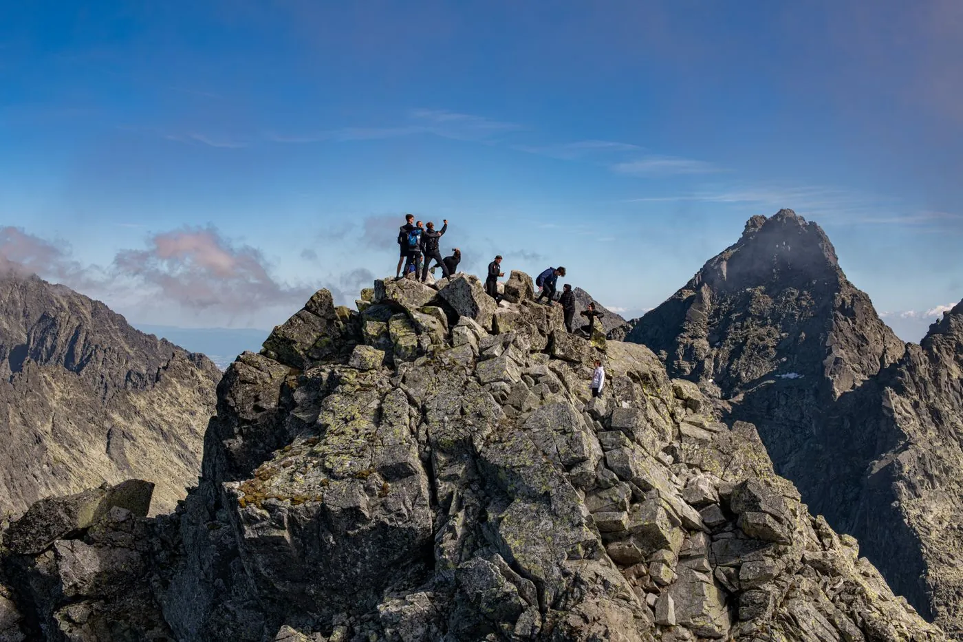 Turisté na skalnatém vrcholu nad okolními štíty