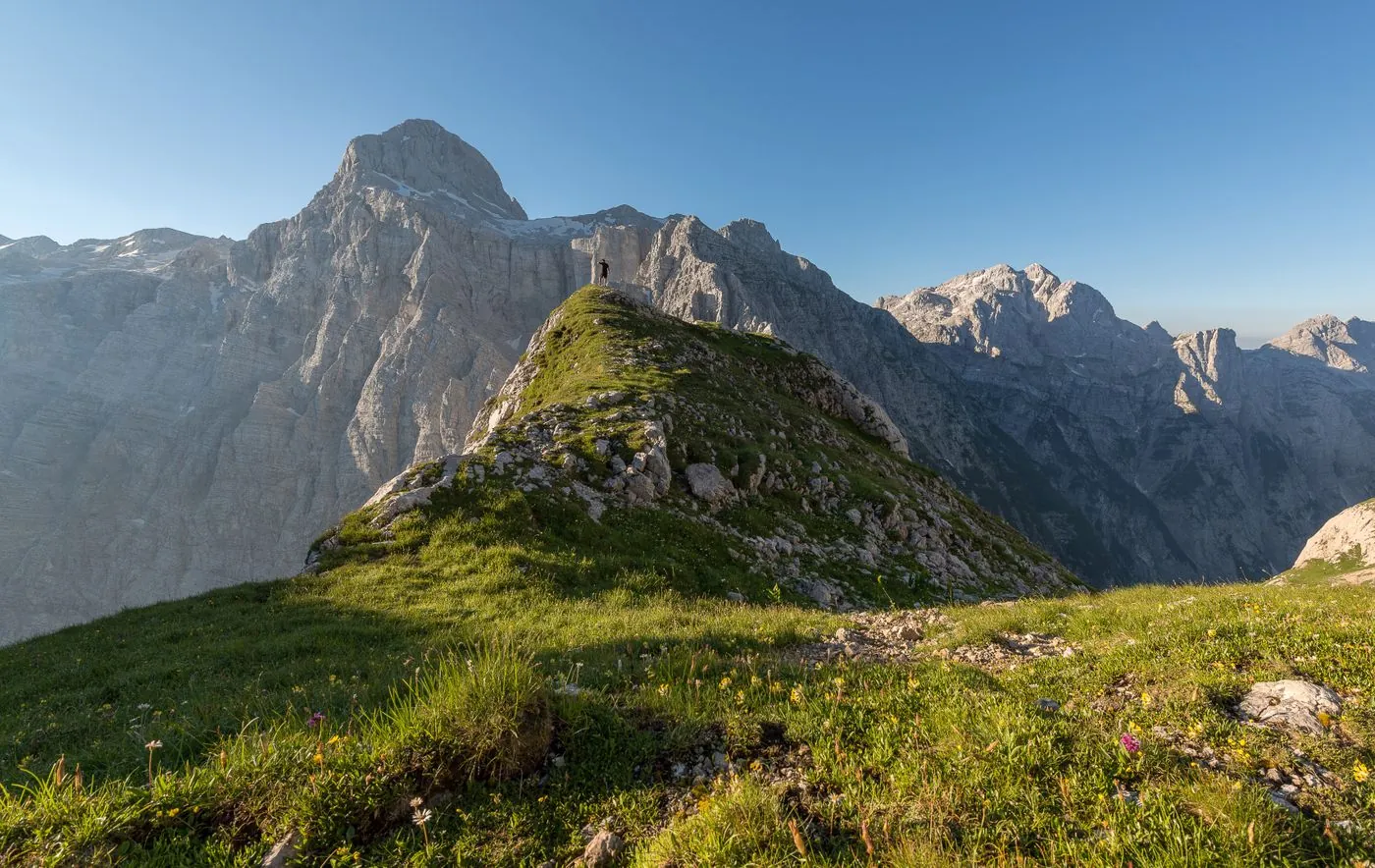 Turista na skalnatém vrcholu nad zeleným hřebenem