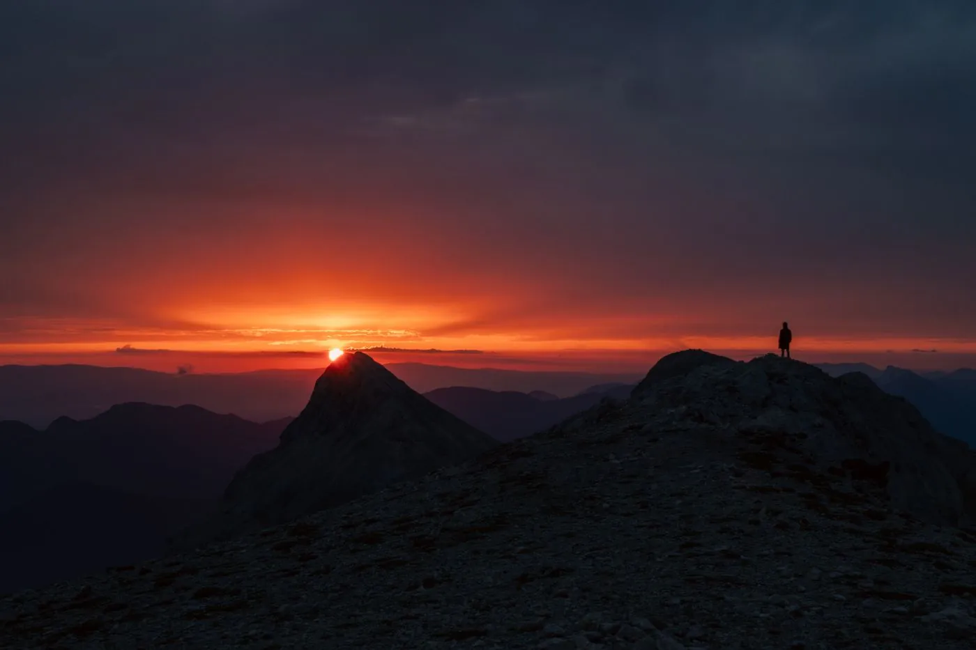 Silueta osoby na vrcholu při západu slunce