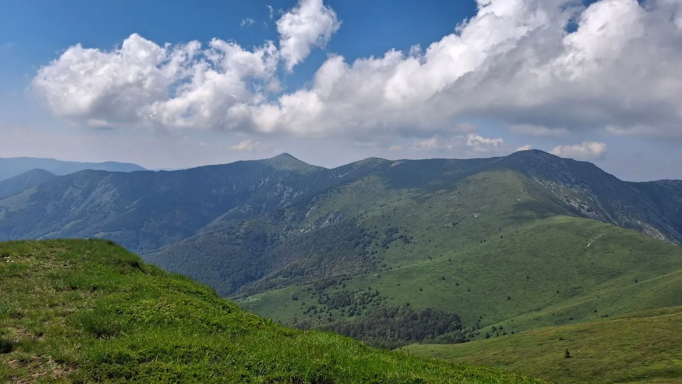 Zelené horské hřebeny pod oblačnou oblohou